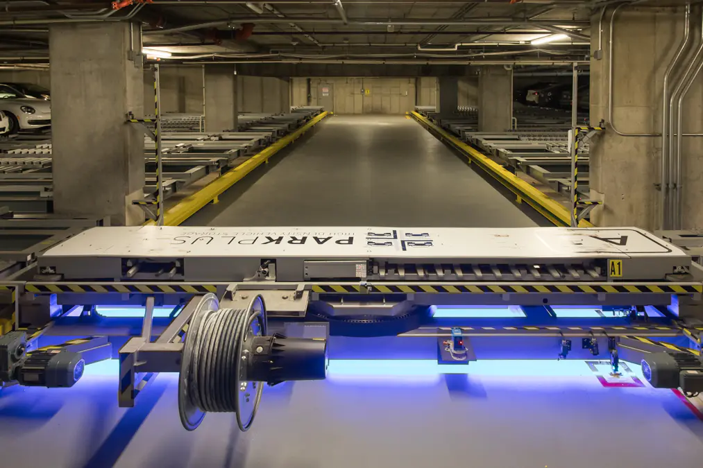 Rack and rail robotic shuttle transferring a vehicle in the parking vault